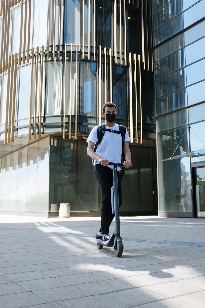 man in blue dress shirt and blue denim jeans standing near glass building